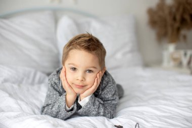 Şirin bir çocuk, beyaz gömlekli bir çocuk, Paskalya süslemesinde yumurta ve çikolatalı tavşanla oynuyor, stüdyo fotoğrafı.