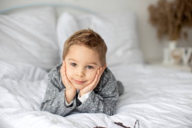 Şirin bir çocuk, beyaz gömlekli bir çocuk, Paskalya süslemesinde yumurta ve çikolatalı tavşanla oynuyor, stüdyo fotoğrafı.