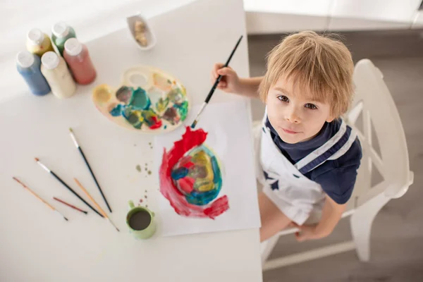 かわいいブロンドの男の子 就学前の子供 バレンタインのためのアクエラレ色のカードで自宅で絵を描く — ストック写真