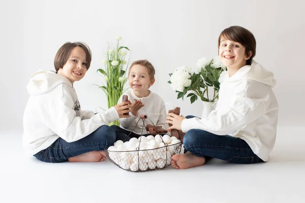 かわいいスタイリッシュな幼児の子供と兄 白いシャツを着た男の子 イースターの装飾で卵とチョコレートバニーで遊んで スタジオショット — ストック写真
