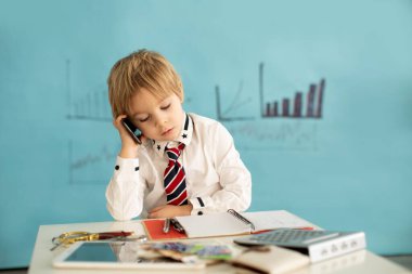 Yakışıklı, şık giyimli çocuk kravatlı sarışın çocuk tablet üzerinde çalışıyor, not alıyor ve telefonda konuşuyor iş konsepti ve fikri.