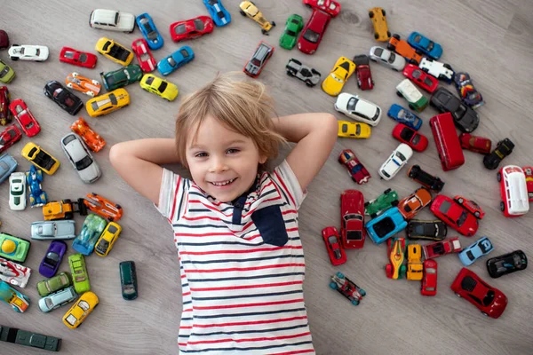 かわいい幼児の子供 ブロンドの男の子 車で遊ぶ 床の上で異なるサイズと色 — ストック写真