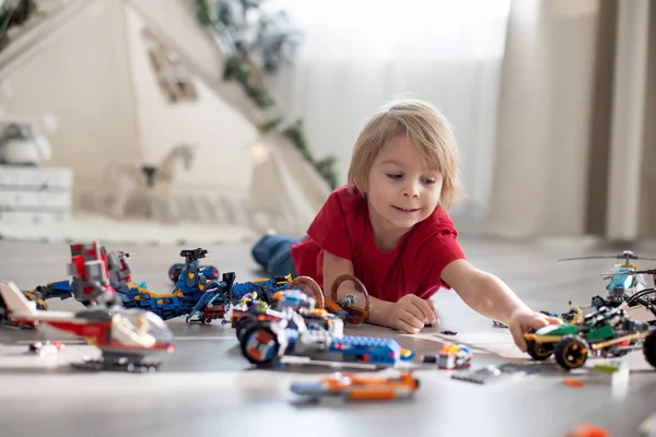 可爱的幼儿 金发男孩 玩彩色塑料块 建筑玩具 制造汽车和飞机 — 图库照片