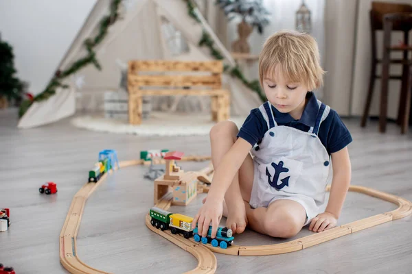 Sevimli Sarışın Çocuk Evdeki Renkli Trenlerle Demiryollarıyla Oynuyor — Stok fotoğraf