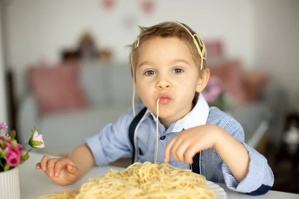 かわいい就学前の子供ブロンドの男の子家でスパゲティを食べてどこでも混乱させる面白い瞬間 — ストック写真