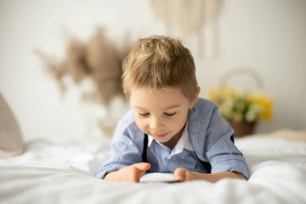 Blond Förskola Barn Söt Pojke Spela Mobiltelefon Sängen Solig Dag — Stockfoto