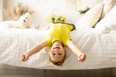 Evcil köpeğiyle birlikte evde yatakta oynayan sevimli bir anaokulu çocuğu.