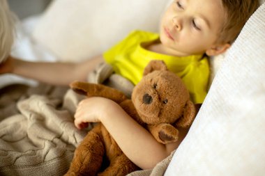 Evcil köpeğiyle birlikte evde yatakta oynayan sevimli bir anaokulu çocuğu.