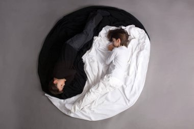 İki çocuk, siyah-beyaz giyinmiş, Yin-Yang çemberinde yerde yatıyor, izole bir görüntü.