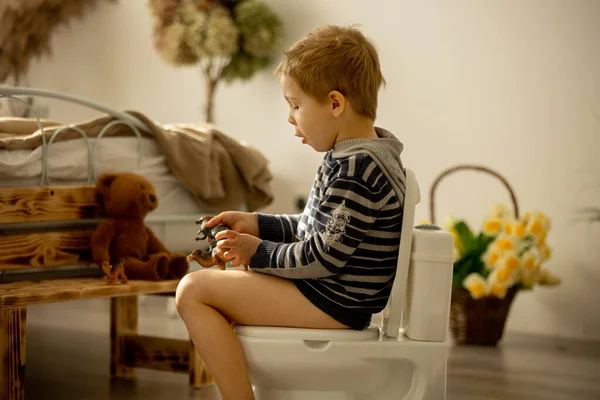 Criança Bonito Menino Usando Potty Casa Enquanto Brincava Com Brinquedos — Fotografia de Stock