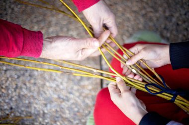 Man, teaching his child how to weave his easter whip from a rod for the holiday