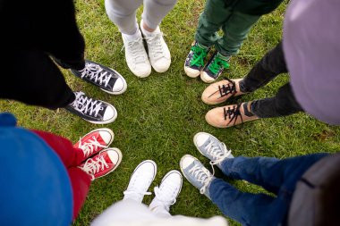 Colorful shoes on children feet. Cool youth colorful white pink green blue black gray gym shoes, people standing in circle, copy place top view