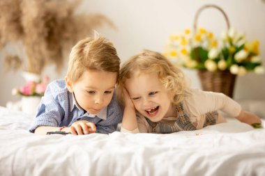 Happy children, siblings, enjoying Easter holiday together, tradition with handmade twig, braided whip made from pussy willow, traditional symbol of Czech Easter
