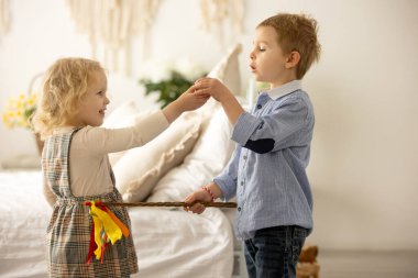 Happy children, siblings, enjoying Easter holiday together, tradition with handmade twig, braided whip made from pussy willow, traditional symbol of Czech Easter