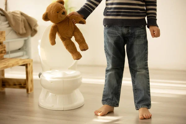 어린아이가 장난감을 가지고 놀다가 바지에 오줌을 아이는 해져서 화장실에 버립니다 — 스톡 사진