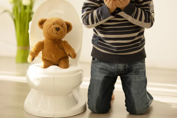 어린아이가 장난감을 가지고 놀다가 바지에 오줌을 아이는 해져서 화장실에 버립니다 — 스톡 사진