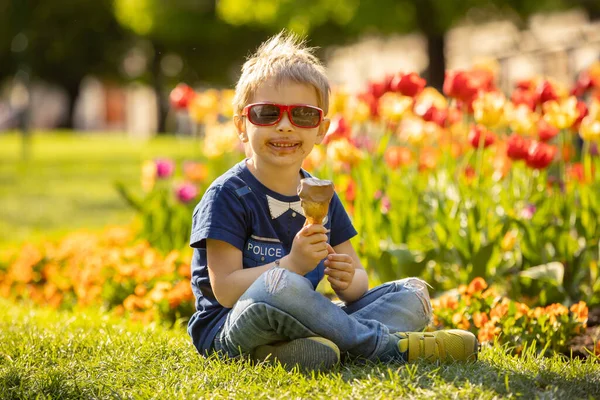 Aranyos Kisgyerek Jégkrémet Eszik Parkban Tavaszi Virágok Veszik Körül Szökőkút — Stock Fotó