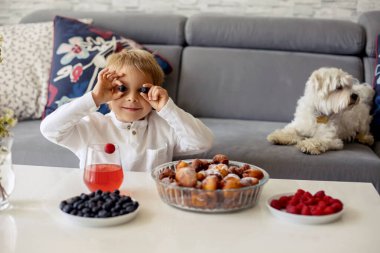 Sevimli bir çocuk, evcil köpeği olan bir çocuk, evde kardeşleriyle kızarmış donut yiyor, tatlı bir kahvaltı yapıyor.