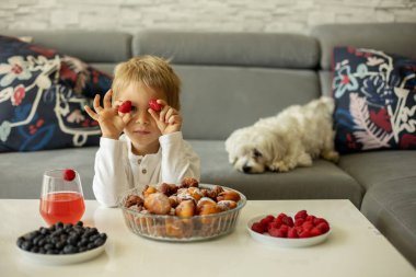 Sevimli bir çocuk, evcil köpeği olan bir çocuk, evde kardeşleriyle kızarmış donut yiyor, tatlı bir kahvaltı yapıyor.