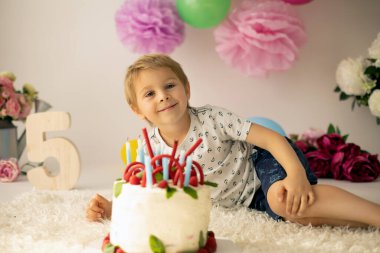 Sevimli çocuk, anaokulu çocuğu, evde ev yapımı pastayla ahududu, nane şekeri, balon ve süslemeyle doğum gününü kutluyor.
