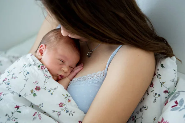 年轻的母亲和新生的男婴躺在床上 抱着男婴 幸福地微笑着 — 图库照片