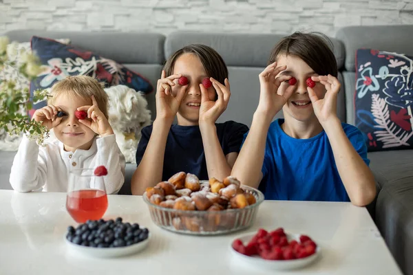 Cute child, boy with pet dog, eating fried doughnuts at home with his siblings, sweet breakfast