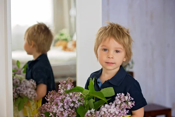 아름다운 금발의 아이의 라일락을 꽃병을 어린아이가 카메라를 거울을 — 스톡 사진