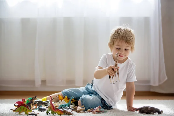 ブロンドの子供 幼児の男の子 自宅でプラスチック製の動物のおもちゃで遊ぶ 柔らかいバックライト — ストック写真