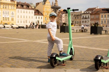 Şirin bir çocuk, anaokulu çocuğu, scooter 'da duruyor, Çek Cumhuriyeti' ni ziyaret ediyor, yazın Ceske Budejovice.
