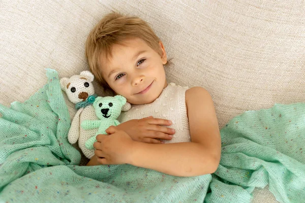 小さな幼児の子供 かわいいです子供とともにニット小さなかわいい動物のおもちゃ ベッドに横たわっています 抱っこ — ストック写真