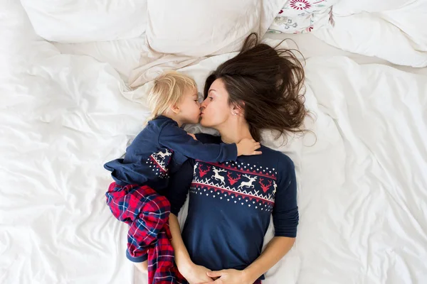 Nice sleepy morning in bed, mom and toddler child, boy, playing, kissing and hugging