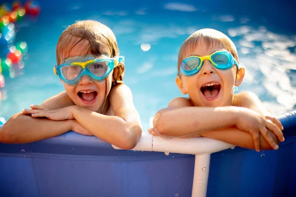 Young child, swimming in the summer in a pool full of colorful balls, enjoying beautiful sunny weather outdoors