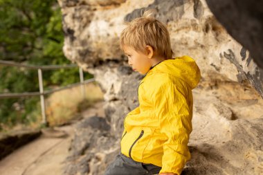 Child, boy, visiting Pravcicka brana in Hrensko, Czech Republic on a rainy summer day with his parents