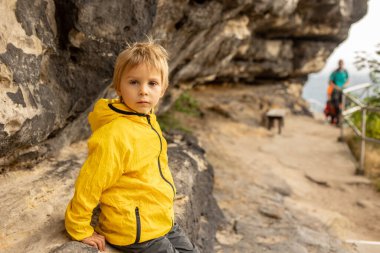 Child, boy, visiting Pravcicka brana in Hrensko, Czech Republic on a rainy summer day with his parents
