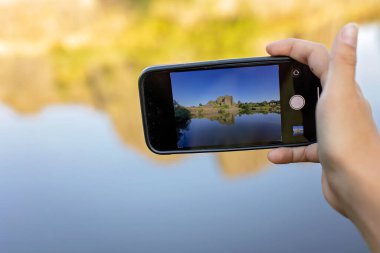 Child, taking picture on mobile of polygonal structures of basalt columns, natural monument Panska skala near Kamenicky Senov, Czech Republic.
