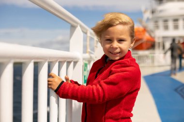 Children, experience ride on a ferry on a fjord, strong wind on the deck of a ferry on a sunny day