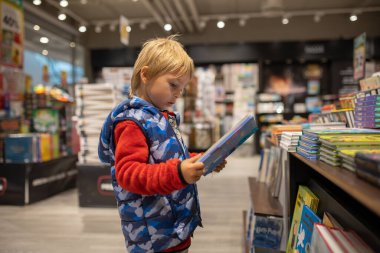 Child, visiting little town in south Norway, Arendal, on a rainy summer day, visiting bookstore