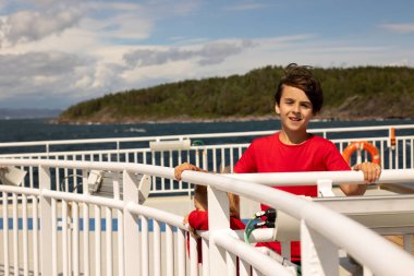Children, experience ride on a ferry on a fjord, strong wind on the deck of a ferry on a sunny day