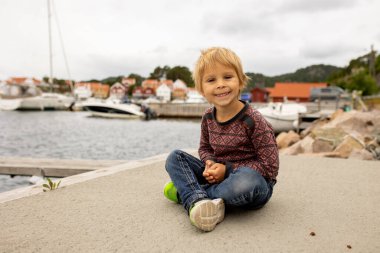 Toddler child, enjoying the view over beautiful small village in south Norway on a cloudy day