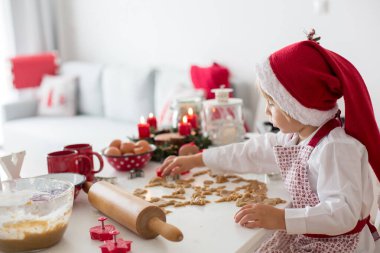 Sevimli sarışın çocuk, çocuk ve annesi evde Noel kurabiyesi pişiriyor, eğleniyor.