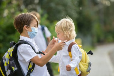 Okul çocukları, çocuklar, yaz tatilinden sonra okula geri dönmek, çocuklar Coronavirus COVID 19 yüzünden maske takarak okula gitmek.