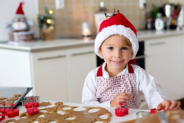 Sevimli sarışın çocuk, çocuk ve annesi evde Noel kurabiyesi pişiriyor, eğleniyor.