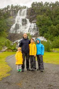 People, visiting Tvinnefossen waterfall, children enjoying the amazing views in Norway to fjords, mountains and other beautiful nature miracles