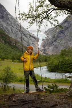 Child, cute blond boy, toddler enjoying the amazing view of the glacier in Jostedalsbreen national park
