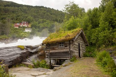 Amazing little wooden small house next to a waterfall on the dock of Hellesylt, child playing in the house, looking out of the window