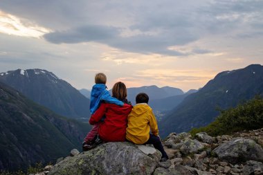 Family with children and dog, hiking in Litlefjellet on sunset, enjoying amazing view from the top of hiking trail Romsdalen