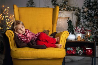 Tatlı çocuk, oğlum, Noel için süslü bir odada sarı bir koltukta oturuyor, rahat bir yer.
