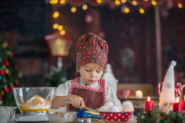 Tatlı sarışın çocuk, yeni yürümeye başlayan çocuk, evde Noel kurabiyesi pişirmek, eğlenmek.
