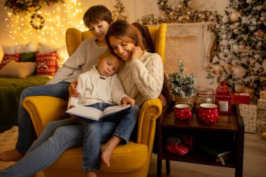 Çocuklar, erkek kardeşler, sarı koltukta oturuyorlar Noel için dekore edilmiş bir odada, rahat bir yerde.