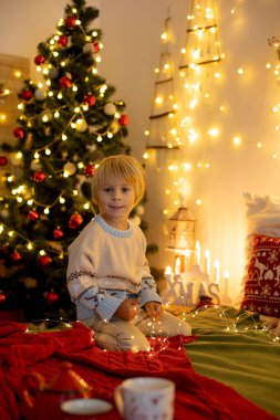 Tatlı çocuk, oğlum, Noel için süslü bir odada sarı bir koltukta oturuyor, rahat bir yer.